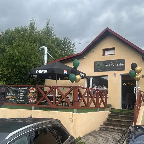 Żółty budynek bistro z drewnianym tarasem